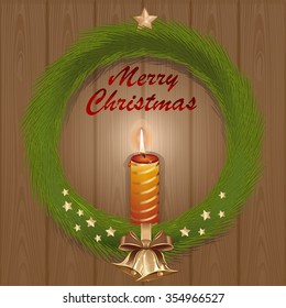 Wreath of fir branches with golden bells and burning candle on a wooden background. Greeting Christmas card.