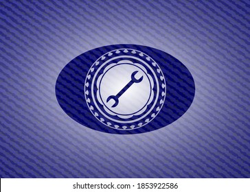 wrench icon inside emblem with high quality denim textured background. 