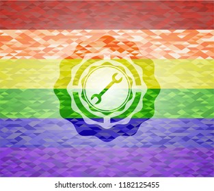 wrench icon inside emblem on mosaic background with the colors of the LGBT flag