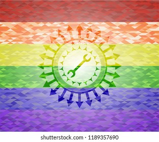 wrench icon inside emblem on mosaic background with the colors of the LGBT flag