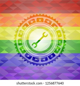 wrench icon inside emblem on mosaic background with the colors of the LGBT flag