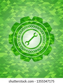 wrench icon inside green mosaic emblem