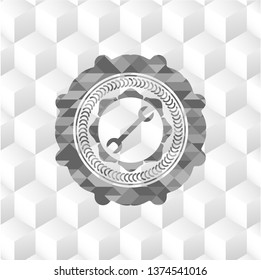 wrench icon inside grey badge with geometric cube white background