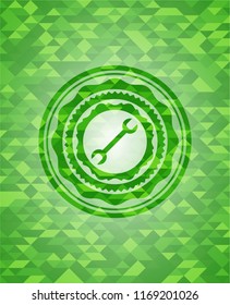 wrench icon inside realistic green mosaic emblem