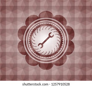 wrench icon inside red seamless badge with geometric background.