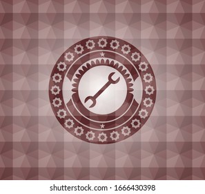 wrench icon inside red seamless emblem with geometric pattern.