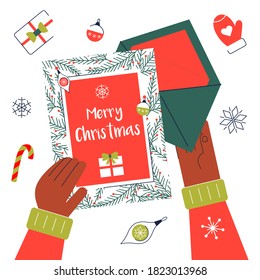 Write chritmas greeting card for family and friends. Hands open letter with xmas postcard. Winter holidays wishes. Top view on the table.