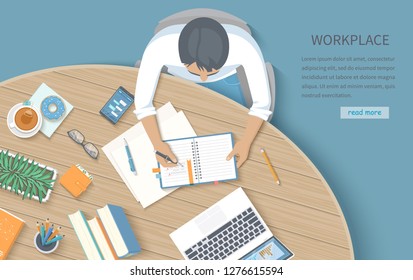 Мan writing notes in a notebook at a round wooden desk. Workplace Desktop Workspace Office supplies, laptop, books, phone, glasses, pen, paper, tea, donuts, flowerpot. Vector Top view 