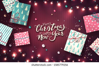 Xmas background with christmas lights, baubles, gift boxes and confetti. Holiday glowing garlands of LED light bulbs on knitted texture. Decorations of realistic colorful lamps for new year cards
