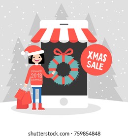 Xmas sale. Millennial caucasian girl buying christmas gifts online. Mobile online store. Seasonal discounts. Winter. Snowy weather. Cheerful wearing knitted red sweater and holding  shopping bags