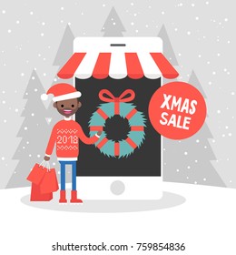 Xmas sale. Millennial character buying christmas gifts online. Mobile online store. Seasonal discounts. Winter. Snowy weather. Cheerful black boy wearing knitted red sweater and holding
 shopping bag