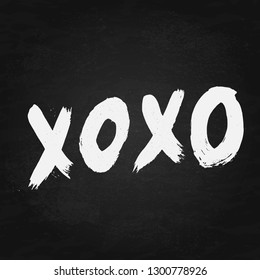 XOXO hand written phrase on chalckboard background. Hugs and kisses sign. Grunge brush lettering XO. Easy to edit template for Valentine’s day greeting card, banner, poster, flyer, postcard.