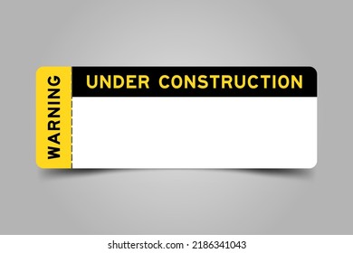 Yellow and black color ticket with word warning and under construction and have white copy psace on gray background