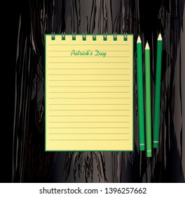Yellow notebook with template hand-drawn Green festive bunting with clover and pencil. Irish holiday - Happy St. Patrick's Day with a garland of three-leaf. Greeting card. Vector on wooden back