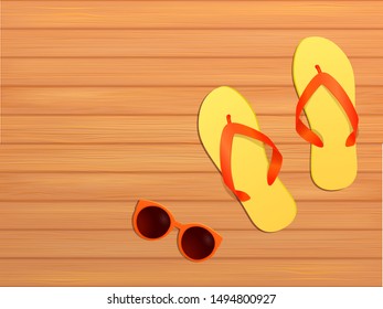 Yellow and red flip flops with sunglasses on wooden floor on summer day