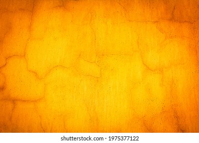 Yellow wall in spots, cracks, stains. Painted concrete wall in abstract grunge style. Grunge background orange texture for backgrounds, portraits, posters.