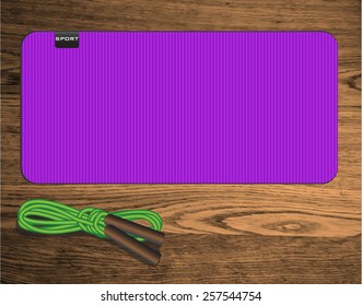 yoga mat on wood texture floor with green skipping rope