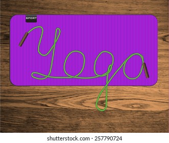 yoga mat on wood texture floor with green lettering "yoga"