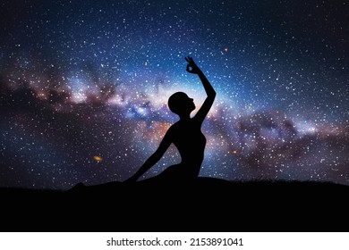 Yogi girl silhouette on grass. Woman doing yoga at night. Milky Way