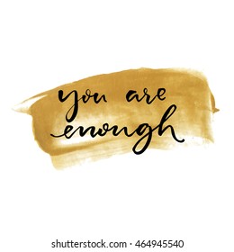 You are enough. Inspirational quote handwritten on golden paint stroke