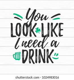 You Look Like I Need A Drink funny handdrawn dry brush style lettering on white wooden background, 17 March St. Patrick's Day celebration. Suitable for t-shirt, poster, etc., vector illustration