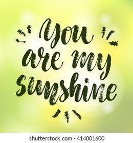 "You are my sunshine" vector text on defocus  blur color background. Hand drawn lettering for greeting card, prints and posters. Motivation inspiration typographic inscription, calligraphic design