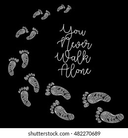 "You never walk alone " handwritten with footprints in decorative style.