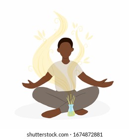 Young african american man sitting in lotus pose with aroma diffuser. Aromatherapy and relax. Self care at home.