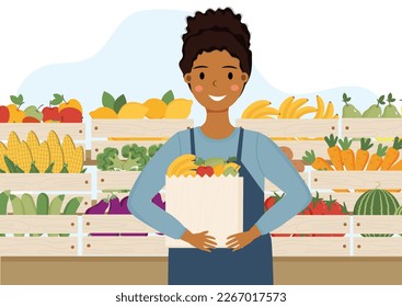 Young african american woman shop assistant in fruit and vegetable shop. Female shop assistant is standing near counter with bag in her hands. Young woman is selling fruits and vegetables.