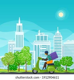 Young african guy in protective face mask with box for food delivery rides a green scooter on a spring background of green trees and cities, online delivery service and stay home concept