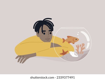 A young African person watching a goldfish swimming in a round water tank