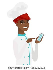 Young african-american chef cook holding mobile phone and pointing at it. Smiling chef cook using a mobile phone. Vector flat design illustration isolated on white background.