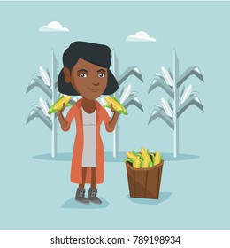 Young african-american farmer standing near basket with corn and holding corn cobs in hands on the background of corn field. Happy farmer collecting corn. Vector cartoon illustration. Square layout.
