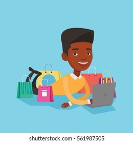 Young african-american man using laptop for shopping online. Smiling customer lying with laptop and shopping bags around him. Man doing online shopping. Vector flat design illustration. Square layout.