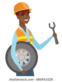 Young african-american mechanic in uniform and hard hat holding spanner and wheel. Smiling mechanic with tyre and spanner. Vector flat design illustration isolated on white background.