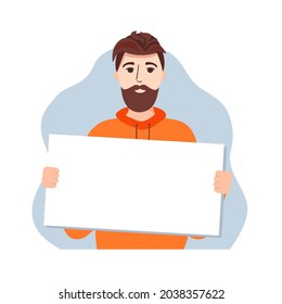 A young bearded man holds an empty poster. The guy is holding a piece of paper.