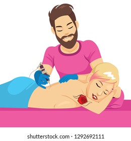 Young bearded tattoo master making tattoo on woman back