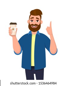 Young Bearded Trendy Man Holding A Coffee Cup And Pointing Up Index Finger. Male Character Design Illustration. Modern Lifestyle, Food And Drink Concept In Vector Cartoon Style.