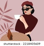 A young beautiful brunette woman with a short hairstyle in a beret sits in a cafe and drinks coffee. French style in clothes. Fashionable girl with sunglasses holds a cup of hot drink, tea, coffee