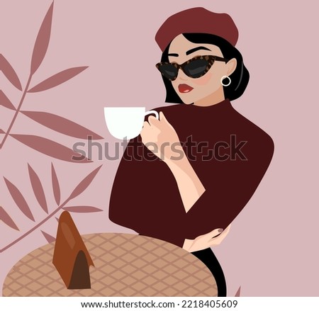 A young beautiful brunette woman with a short hairstyle in a beret sits in a cafe and drinks coffee. French style in clothes. Fashionable girl with sunglasses holds a cup of hot drink, tea, coffee
