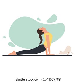 Young beautiful flexible girl doing yoga at home with pet. 