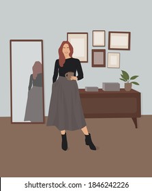 Young beautiful girl with long wavy hair in a dark-grey sweater and long dark skirt holding a mug of coffee in the furnished room