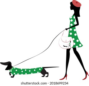 A young beautiful girl is on a walk with a dachshund also known as the wiener dog, badger dog, sausage dog .