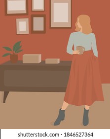 Young beautiful girl with short blond wavy hair in a long red skirt holding a mug of coffee in the furnished room