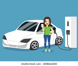 Young beautiful woman charging electro car at electric gas station