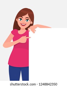 Young beautiful woman smiling and holding a blank / empty sheet of white paper or board and pointing with index finger. Human emotion & body language concept illustration in vector cartoon flat style.