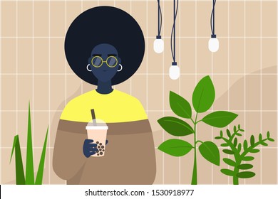 Young black female character holding a cup of boba bubble tea to take away in a modern hipster interior with plants and tile pattern