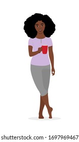 A young black girl with an Afro hairstyle stands barefoot, leans on one leg, smiles and drinks coffee from a red mug. Vector stock flat illustration isolated on a white background