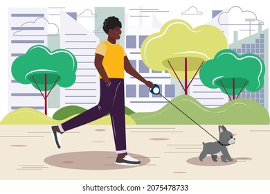 Young Black Man Walking With A Dog In The Park. Dark Skin Man Walking With A French Bulldog In The City Park. 