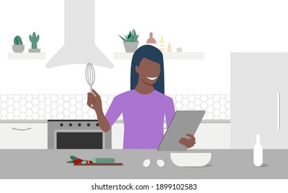 A young black woman looks on tablet and cooking by online video tutorial in her kitchen. Online culinary school. Online courses, e-learning. Eps 10